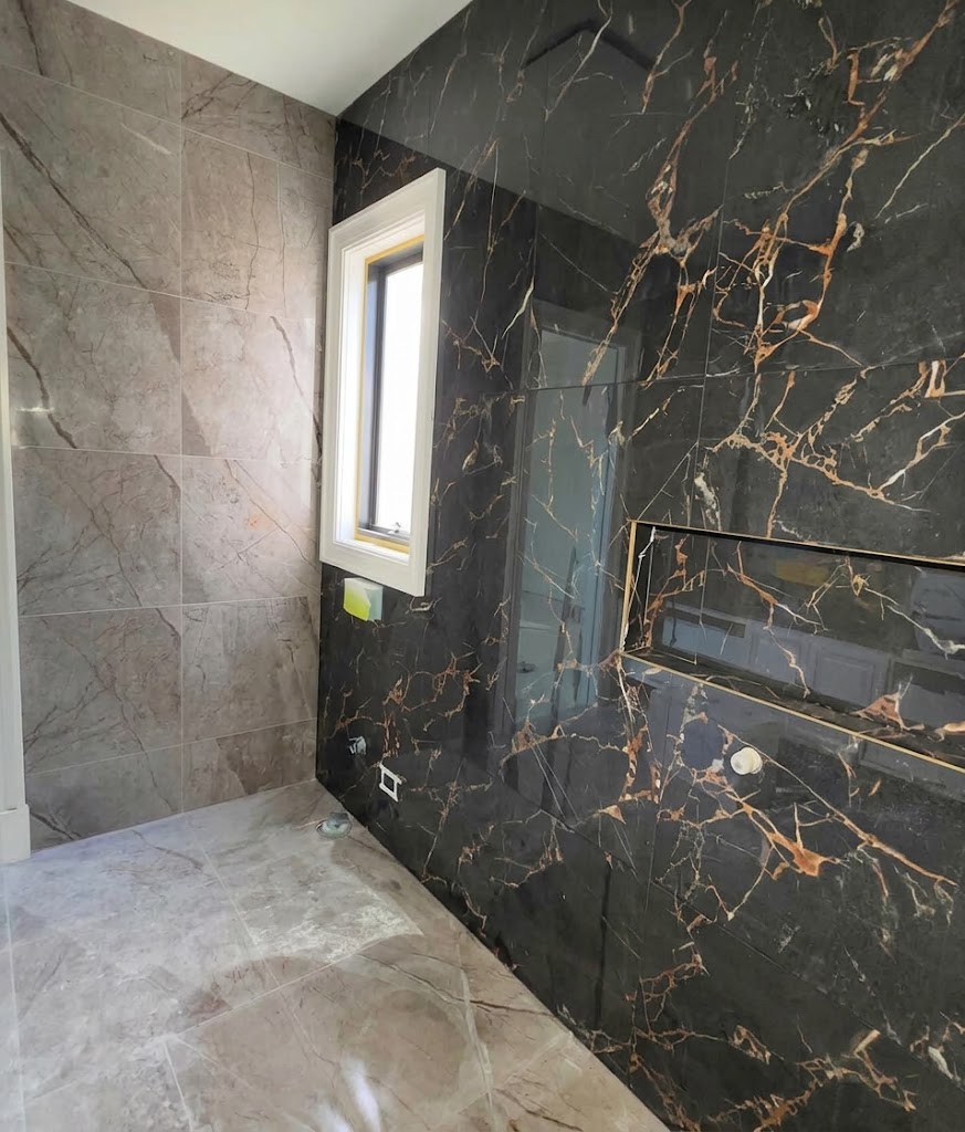 Shower wall in black marble-look tiles with gold veining, a tiled niche and grey stone-look floor tiles