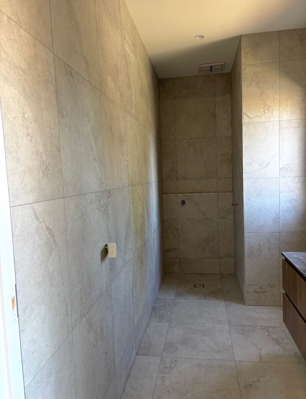 Bathroom with large-format stone-look wall and floor tiles and a walk-in shower