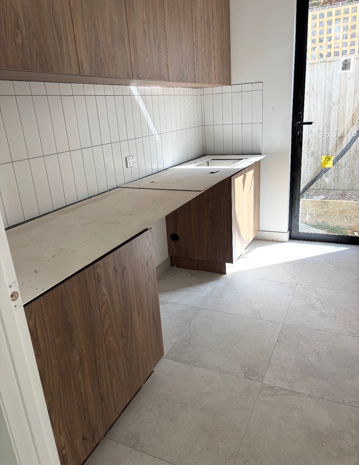 Laundry with a white vertical stack-bond tiled splashback and large-format grey floor tiles