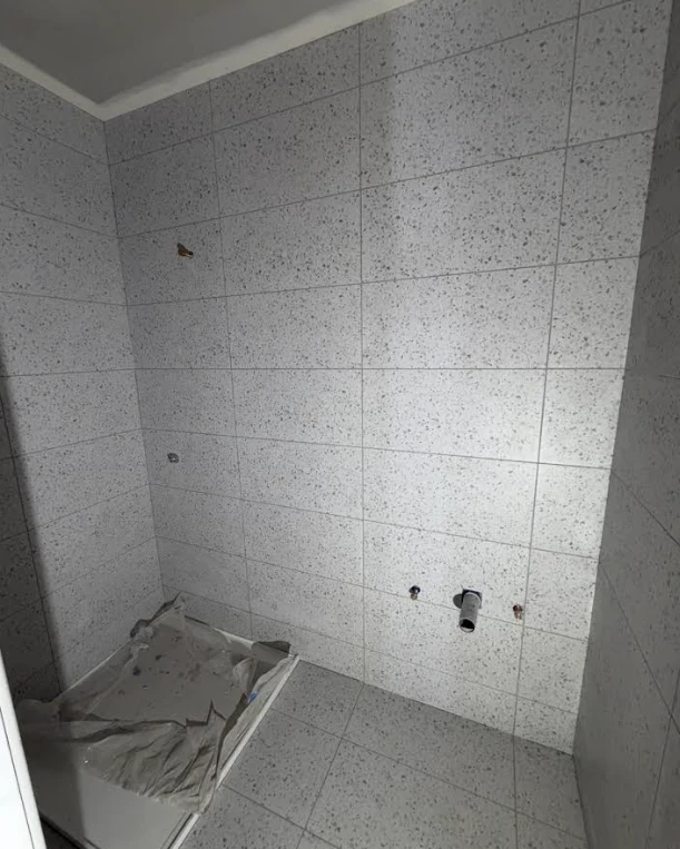 Shower recess tiled in large-format terrazzo-look wall and floor tiles