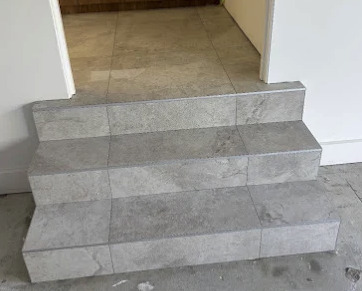 Staircase tiled in grey stone-look tiles with matching risers